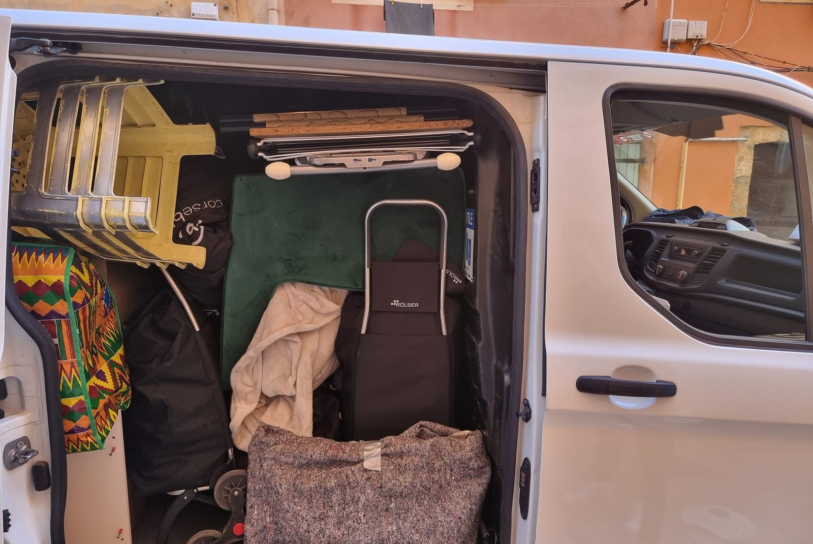 Chargement d'un véhicule utilitaire pour un déménagement en Corse avec meubles, chaises empilées, poussette et objets protégés